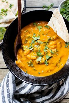 a bowl of soup with tortilla chips and cilantro on the side