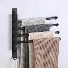 the towel rack is holding four different colored towels and two black metal hooks on it