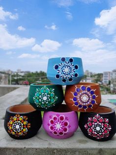 colorful bowls are stacked on top of each other in front of the water and sky