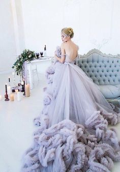 a woman in a dress sitting on a couch surrounded by candles and flowers with her back turned to the camera