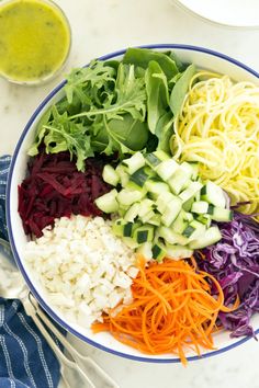 a bowl filled with noodles and veggies next to a glass of green juice