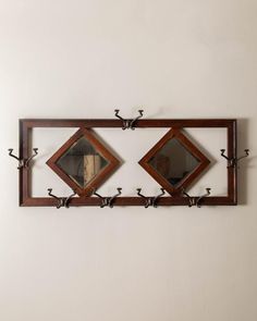 two mirrors mounted to the side of a wall above a shelf with hooks on it