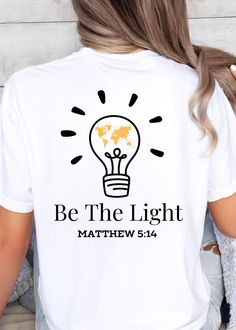 **DESCRIPTION** Illuminate your faith with this inspiring "Be the Light" t-shirt, featuring a vibrant graphic of a light bulb filled with a yellow map of the Earth. Inspired by Matthew 5:14, this design serves as a powerful reminder that we are called to shine our light in the world, spreading hope and love to all corners of the Earth. Perfect for everyday wear, this shirt is a stylish way to share your faith and encourage others to reflect Christ's light in their lives. **SHIRT DETAILS** Comfor Christian Tee Shirt Designs, Be The Light Svg, Be The Light Tshirt Designs, Be The Light Sweatshirt, Faith Based T Shirts, Faith Based Shirt, Faith Shirts, Christian Tee Shirts, Matthew 5