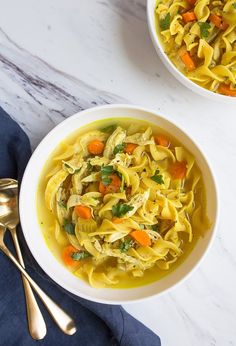 two bowls filled with chicken noodle soup on top of a table