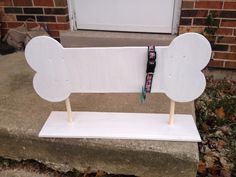 a white bench sitting in front of a brick building with two toothbrushes sticking out of it