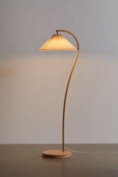 a floor lamp with a wooden base and a white shade on the top, sitting on a table