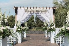 an outdoor wedding ceremony with white flowers and greenery