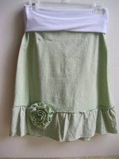 a green skirt hanging on a wall with a flower in the center and a white t - shirt underneath it