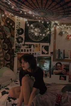 a woman sitting on top of a bed in a room filled with posters and lights