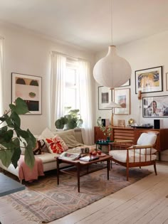 a living room filled with lots of furniture and pictures on the wall next to a window