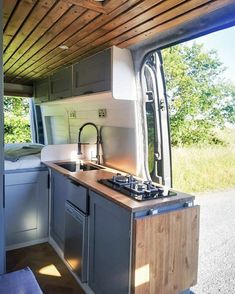 the kitchen is built into the side of the vehicle and has wood paneling on the ceiling