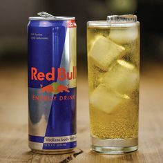 a can of red bull energy drink next to a glass with ice