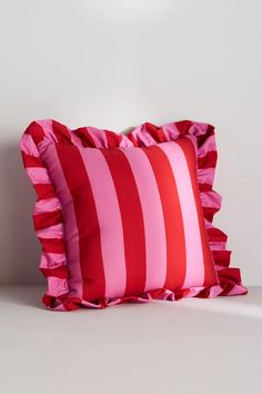 two red and white striped pillows with ruffles on them sitting next to each other