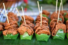 several skewered food items on a banana leaf with toothpicks stuck in them