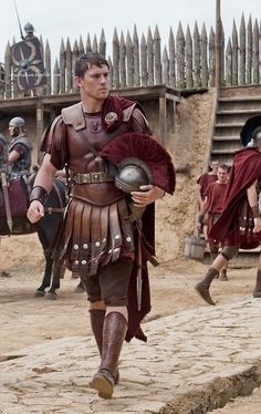 men dressed in roman armor walking on dirt