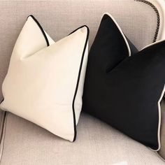 two black and white pillows sitting on top of a couch