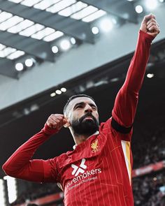 a man with a beard is raising his arms in the air at a soccer game