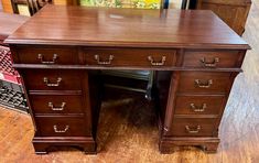 a wooden desk with drawers on it in a room filled with wood floors and furniture