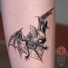 a black and white photo of a bat tattoo on the leg