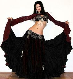 a woman in a black and red belly dance outfit with her hands on her hips