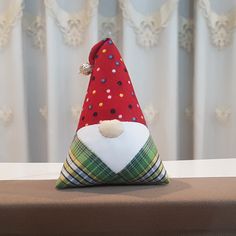 a red and green christmas hat sitting on top of a brown table next to a curtain