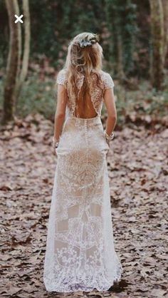 a woman standing in the woods with her back to the camera, wearing a wedding dress