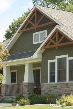 a house with stone and wood trim on the front porch, covered in shingles