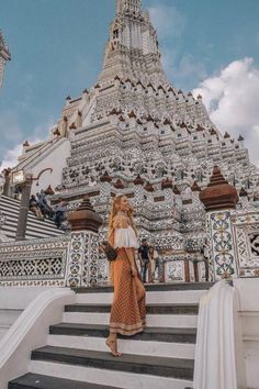 a woman is standing on the steps in front of a building that has ornate architecture