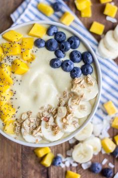 a bowl filled with bananas, blueberries and granola on top of a wooden table