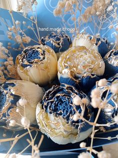 an arrangement of blue and white flowers in a vase with gold foiled decorations on it