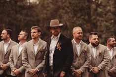 a group of men standing next to each other wearing suits and ties with flowers on their lapels