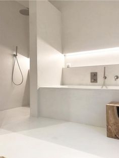 an empty bathroom with white walls and flooring, along with a wooden stand in the middle