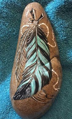 a painted rock with feathers on it