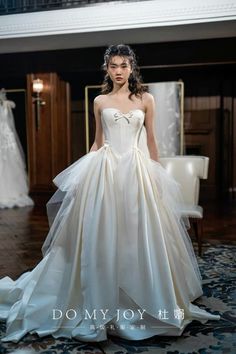 a woman in a wedding dress standing on the floor