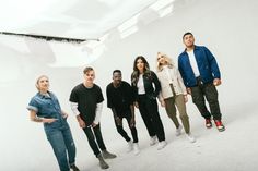 a group of people standing next to each other in front of a white wall with one person looking up at the camera