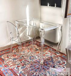 two clear chairs sitting on top of a rug next to a glass table and chair