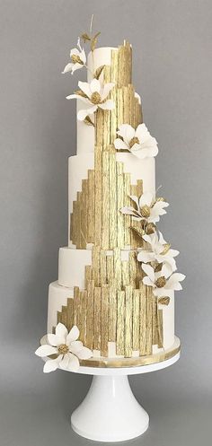 a white and gold wedding cake with flowers on top