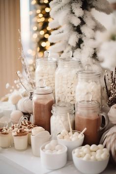 a table topped with jars filled with marshmallows next to a christmas tree