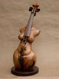 a wooden sculpture of a bear holding a violin on top of it's back