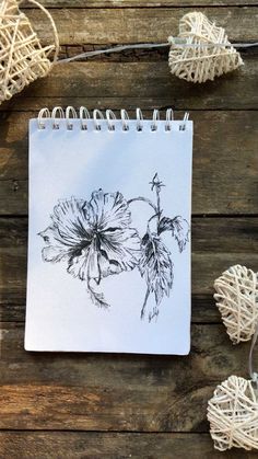 a spiral notebook with a drawing of a flower on the cover and string attached to it