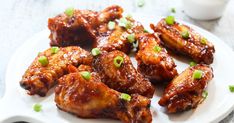 chicken wings with sauce and scallions on a white plate