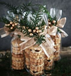 three glass jars filled with cookies and greenery