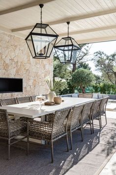 an outdoor dining area with table, chairs and hanging lantern lights on the outside wall