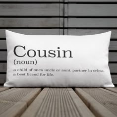 a pillow with the words cousin on it sitting on a wooden bench in front of a wall