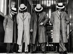 three men in long coats and hats standing next to each other