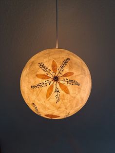 a wooden light hanging from a ceiling with flowers on the top and leaves on the bottom