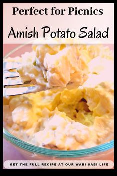 a bowl filled with potato salad on top of a wooden table next to a fork