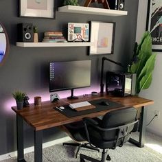 a desk with a computer on it in front of a wall mounted speakers and pictures