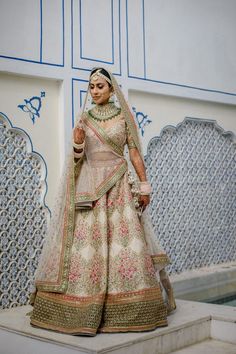 a woman in a bridal gown standing on a ledge with blue and white walls behind her