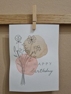 a piece of paper hanging from a clothes line with flowers on it that says happy birthday